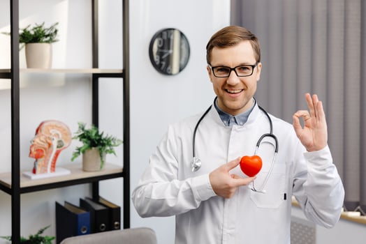 Doctor holding a red heart at hospital office. Medical health care and doctor staff service concept. photo