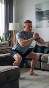 Middle adult man doing squats and exercising in living room at home photo