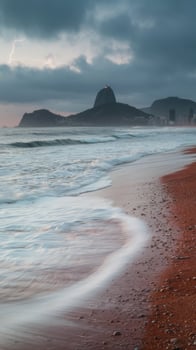 A beach with waves and a mountain in the background photo