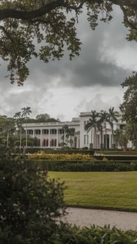 A large white building with a green lawn and trees photo