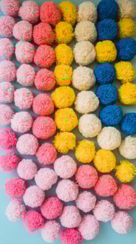 A wall of colorful pom poms on a blue background photo