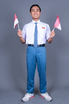 Indonesian Boy High School Student in Uniform Waving Indonesian Flag photo