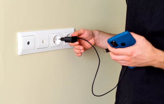 Hand inserting smarthone charger into socket photo