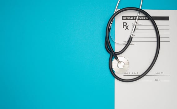 Top view of a stethoscope over the medical prescription sheet on a blue background. photo