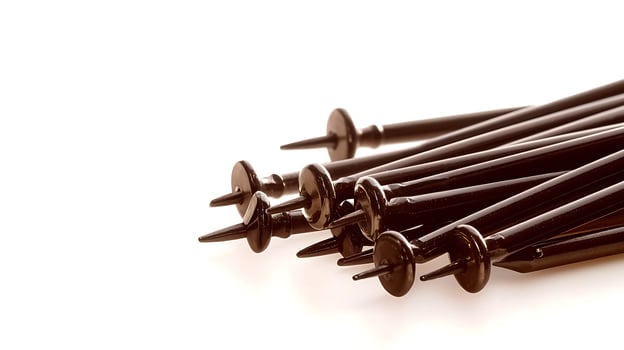 A collection of black golf tees neatly arranged on a light background, ideal for sports and leisure themes photo