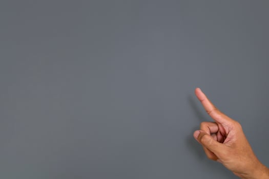 A man's hand with a pose or gesture pointing with index finger at something on a gray background photo