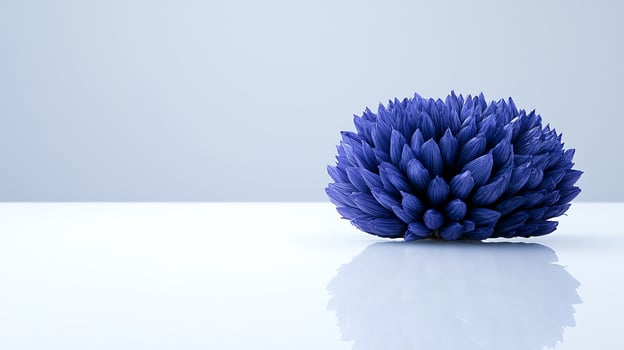 A vibrant blue flower sculpture resting on a reflective surface against a minimalist background photo
