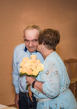 Senior Russian 75 years old couple celebreating golden wedding and kissing in cheek in marriage registry, Russian inscriptions of their medals say 50 years wedding anniversary photo