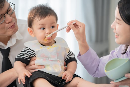 Parents feeding their young child at home during mealtime in a cozy kitchen setting photo