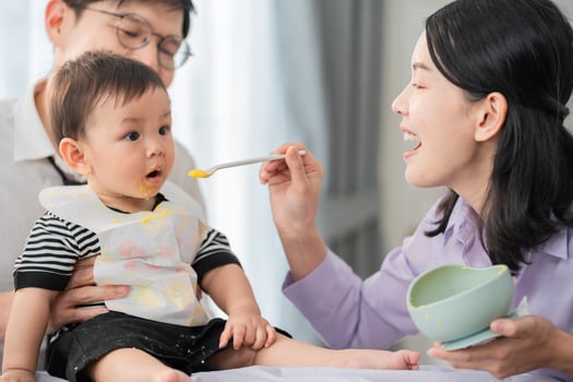 Parents feeding a young child during mealtime at home in a bright and cheerful setting photo