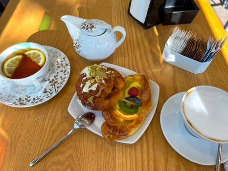 View of the table set for breakfast with hot drinks and sweet pastries photo
