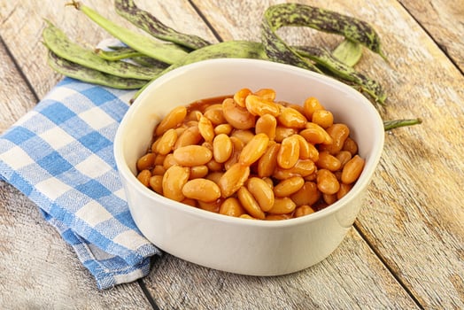 A bowl of beans and a green bean on a table photo