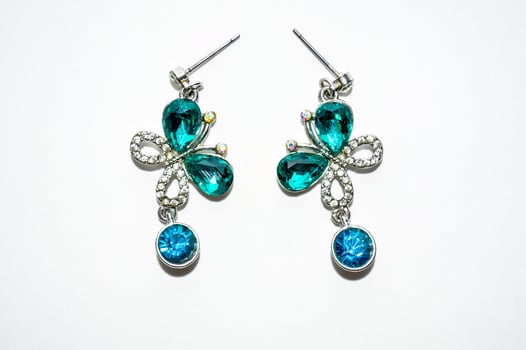 Pair of female silver earrings with shiny crystals and butterflies isolated on white background photo