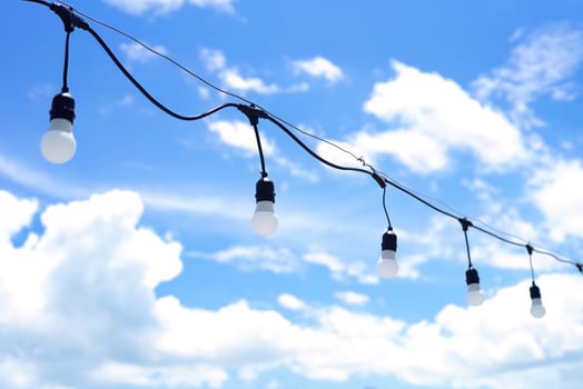 a lot of light bulbs hanging against a blue sky with clouds photo