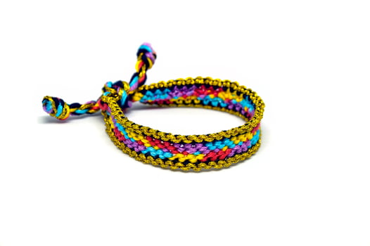 one golden woven DIY friendship bracelet handmade of embroidery bright thread with knots isolated on white background photo