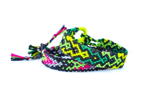 2 tied Multicolored woven DIY friendship bracelets handmade of embroidery bright thread with knots isolated on white background photo