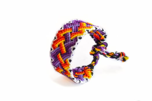 purple orange DIY friendship bracelets handmade of embroidery bright thread with knots isolated on white background photo