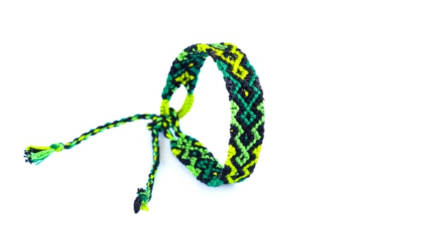 green woven DIY friendship bracelet handmade of embroidery bright thread with knots isolated on white background photo
