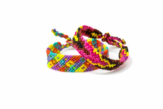 2 Multicolored woven DIY friendship bracelets handmade of embroidery bright thread with knots isolated on white background photo