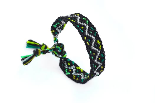 black green woven DIY friendship bracelet handmade of embroidery bright thread with knots isolated on white background photo