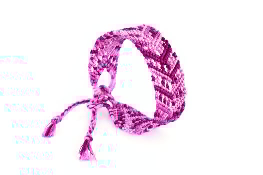 lilac woven DIY friendship bracelets handmade of embroidery bright thread with knots isolated on white background photo