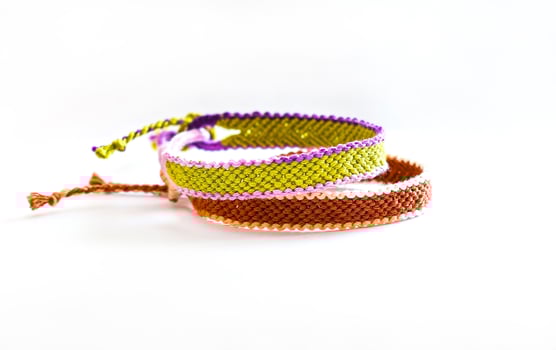 two tied DIY friendship bracelets handmade of embroidery bright thread with knots isolated on white background photo