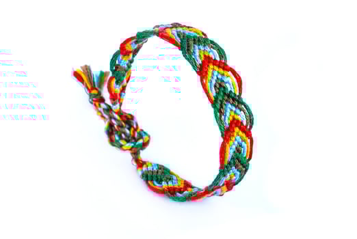 pigtail multicolored woven DIY friendship bracelet handmade of embroidery bright thread with knots isolated on white background photo