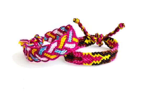 2 tied pink woven DIY friendship bracelets handmade of embroidery bright thread with knots isolated on white background photo