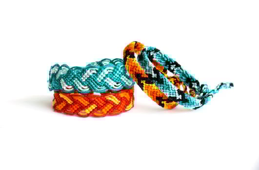 blue and orange woven DIY friendship bracelets handmade of embroidery bright thread with knots isolated on white background photo