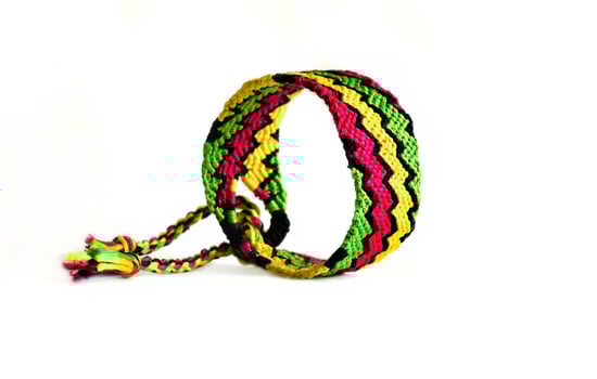 one bright woven DIY friendship bracelet handmade of embroidery bright thread with knots isolated on white photo