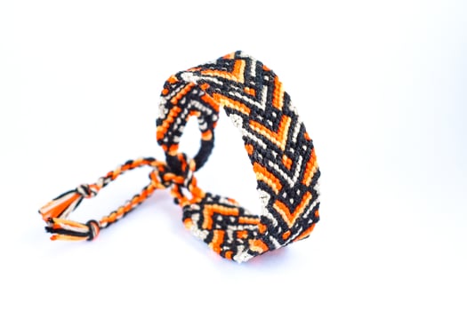 orange DIY friendship bracelets handmade of embroidery bright thread with knots isolated on white background photo