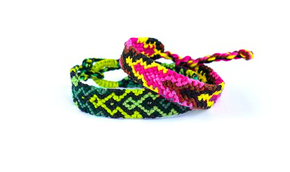green and pink woven DIY friendship bracelets handmade of embroidery bright thread with knots isolated on white background photo
