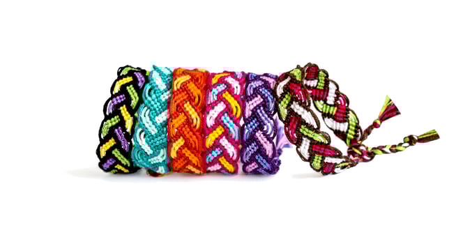 5 multicolored woven DIY friendship bracelets made of embroidery bright thread with knots isolated on white background photo