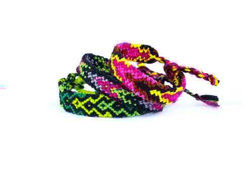 3 tied woven DIY friendship bracelets handmade of embroidery bright thread with knots isolated on white background photo