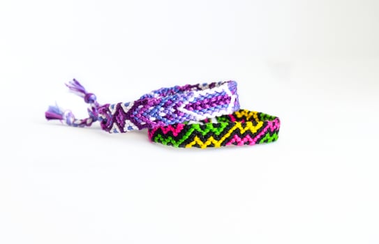 2 tied woven friendship bracelets handmade of embroidery bright thread with knots isolated on white background photo