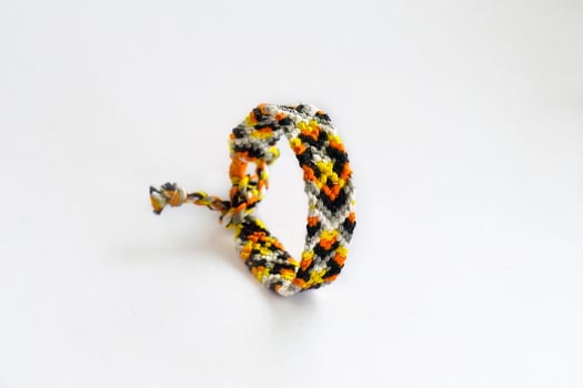 one woven DIY friendship bracelets handmade of embroidery bright thread with knots isolated on white background photo