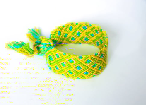 yellow green DIY friendship bracelets handmade of embroidery bright thread with knots isolated on white background photo