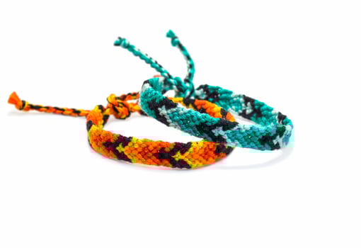 tied blue and orange woven DIY friendship bracelets handmade of embroidery bright thread with knots isolated on white background photo