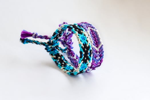 blue and purple woven DIY friendship bracelets handmade of embroidery bright thread with knots isolated on white background photo