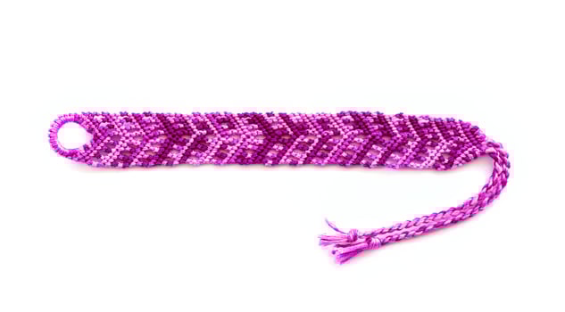 one purple DIY friendship bracelet handmade of embroidery bright thread with knots isolated on white background photo