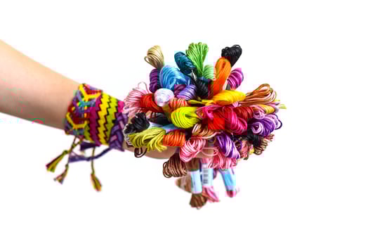 Many embroidery thread for friendship bracelets in hand. Female hand with handmade bracelets on wrists. White background with copy space photo
