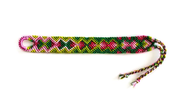 one DIY friendship bracelets handmade of embroidery bright thread with knots isolated on white background photo