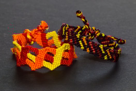 Colorful friendship bracelets with fiery colors handmade of thread with knots isolated on black background photo