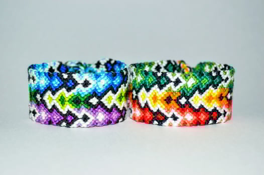 2 tied Multicolored DIY friendship bracelets handmade of embroidery bright thread with knots isolated on white background photo