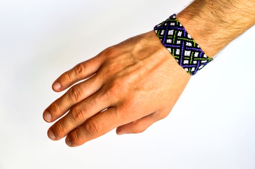 Male hand with colorful friendship bracelet handmade of thread with knots isolated on white background photo