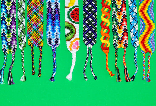 Colorful unique friendship bracelets made of thread with braids isolated on green background photo
