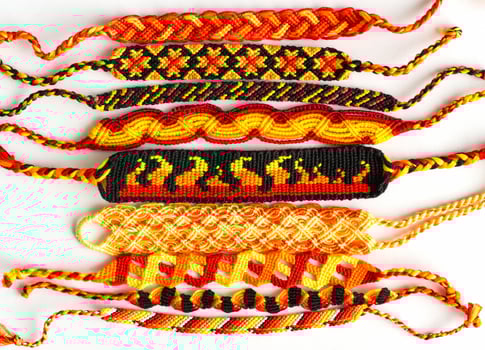 Woven DIY friendship bracelets handmade of embroidery floss with knots. Fire colors photo