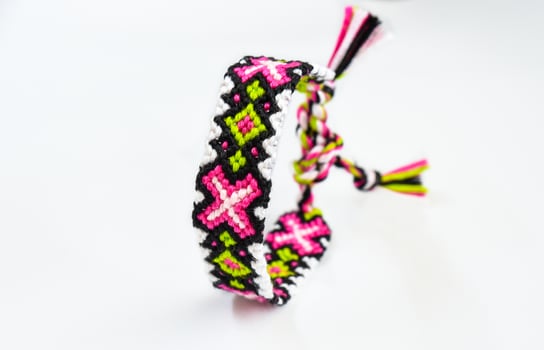 pink and white woven DIY friendship bracelets handmade of embroidery bright thread with knots isolated on white background photo