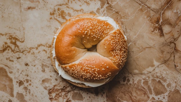 Freshly baked bagel sandwich with cream cheese on marble background photo