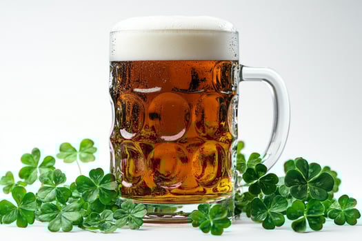 A frosty mug of beer with a rich amber hue, surrounded by vibrant green clovers, evoking a festive atmosphere. photo